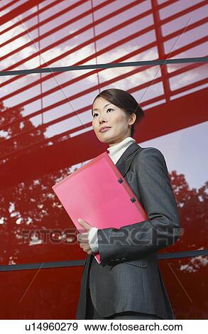 Businesswoman holding notebook, Standing Beside red Building View Large Photo Image Stock Photo - Businesswoman holding notebook, Standing Beside red Building. Fotosearch
