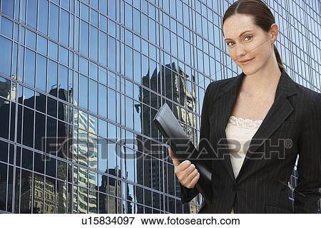 Businesswoman holding portfolio outside office building, portrait View Large Photo Image Stock Photo - Businesswoman holding portfolio outside office building, portrait. Fotosearch