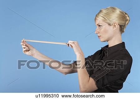 Businesswoman shooting rubber band, on blue background View Large Photo Image Stock Image - Businesswoman shooting rubber band, on blue background. Fotosearch