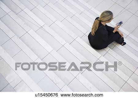 Businesswoman text messaging on steps, outdoors, elevated view View Large Photo Image Stock Photograph - Businesswoman text messaging on steps, outdoors, elevated view. Fotosearch