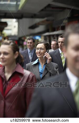 Stock Photo - Businesswoman using mobile phone among crowd in station. Fotosearch