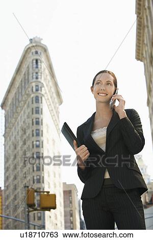 Stock Image - Businesswoman using mobile phone in street. Fotosearch