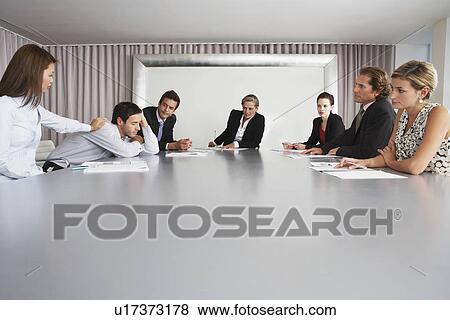 Stock Photo - Businesswoman Waking Sleeping Colleague During Meeting. Fotosearch