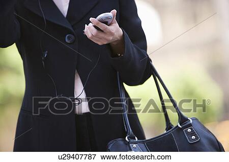 Stock Photo - Businesswoman with handbag and mobile, mid section. Fotosearch