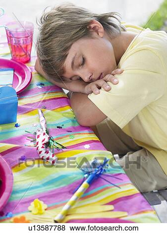 Close-up of boy (7-9) sleeping at table after birthday party View Large Photo Image Stock Photo - Close-up of boy (7-9) sleeping at table after birthday party. Fotosearch