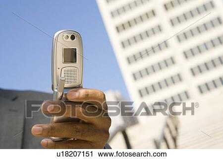 Close-up of businessman's hand with mobile phone, outdoors View Large Photo Image Stock Image - Close-up of businessman's hand with mobile phone, outdoors. Fotosearch
