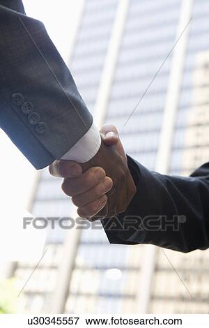 Stock Photo - Close-up of businessmen handshake, outdoors. Fotosearch