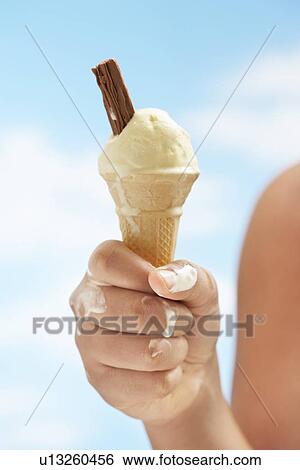 Stock Photograph - Close up of girl (7-9 years) holding icecream, focus on icecream. Fotosearch