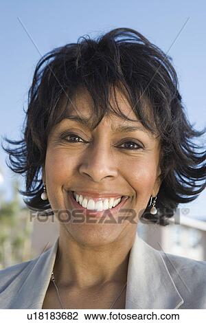 Stock Image - Close-up of mid-adult woman, smiling, outdoors. Fotosearch