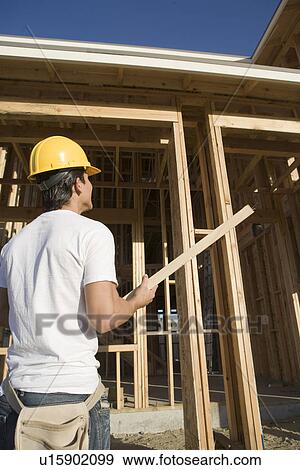Stock Photo - Construction worker carrying wooden beam. Fotosearch
