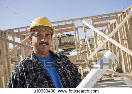 Stock Image - Construction worker holding building plans. Fotosearch