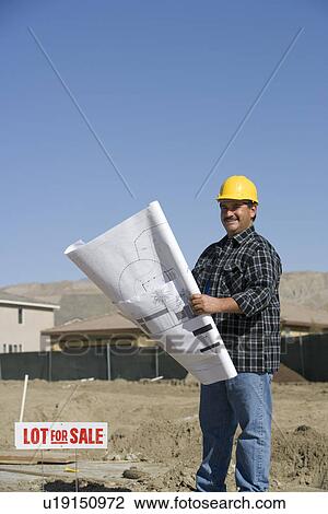 Stock Image - Construction worker holding building plans. Fotosearch