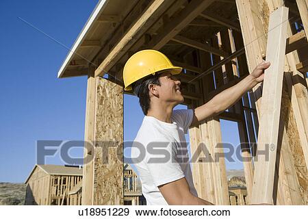 Construction worker holding wooden beam View Large Photo Image Stock Photo - Construction worker holding wooden beam. Fotosearch