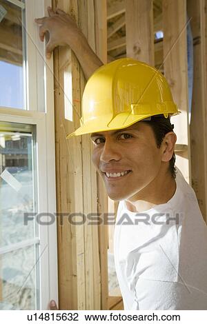 Stock Image - Construction worker installing window. Fotosearch