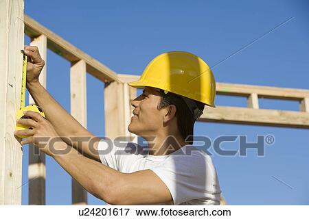Construction worker measuring building construction View Large Photo Image Stock Photo - Construction worker measuring building construction. Fotosearch