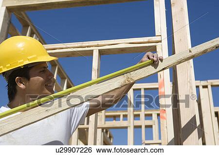Construction worker measuring plank View Large Photo Image Stock Photograph - Construction worker measuring plank. Fotosearch
