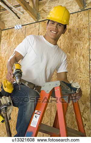 Stock Photo - Construction worker on ladder, portrait. Fotosearch