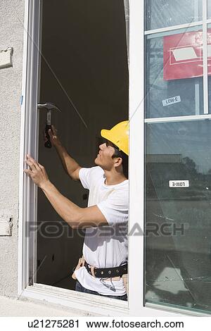 Stock Image - Construction Worker preparing window frame. Fotosearch