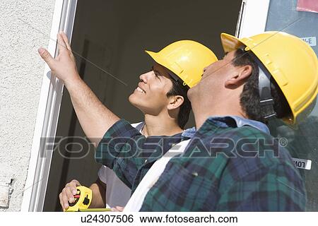 Construction Workers examining window frame View Large Photo Image Stock Photograph - Construction Workers examining window frame. Fotosearch