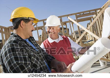 Construction workers observing plans on construction site View Large Photo Image Picture - Construction workers observing plans on construction site. Fotosearch