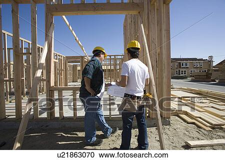 Construction workers reading blueprint on building site View Large Photo Image Stock Image - Construction workers reading blueprint on building site. Fotosearch