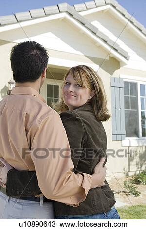 Stock Image - Couple admiring new house. Fotosearch
