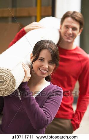 Stock Image - Couple Carrying Rolled Carpet. Fotosearch