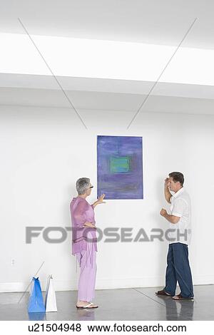 Couple contemplating paintings in gallery View Large Photo Image Stock Photo - Couple contemplating paintings in gallery. Fotosearch