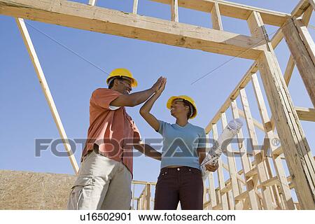 Stock Image - Couple doing 'hi 5' in construction site. Fotosearch