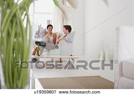 Couple drinking wine in living room View Large Photo Image Stock Photo - Couple drinking wine in living room. Fotosearch