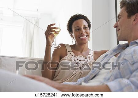 Stock Image - Couple Drinking Wine on Sofa. Fotosearch