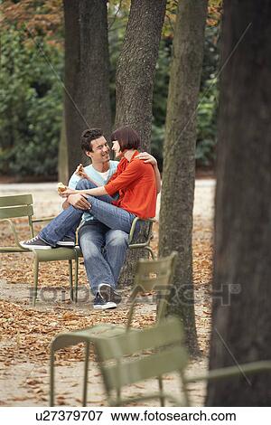 Couple eating snack, sitting on chairs, in park View Large Photo Image Stock Photo - Couple eating snack, sitting on chairs, in park. Fotosearch