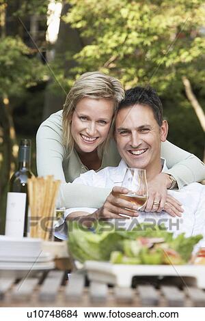 Picture - Couple embracing at outdoor table, portrait. Fotosearch