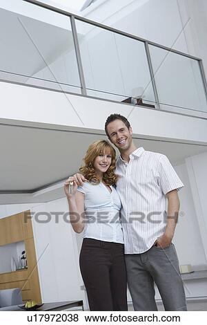 Stock Photo - Couple embracing, woman holding key in new home, portrait. Fotosearch