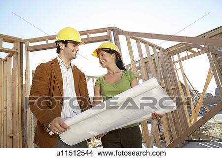 Picture - Couple in front of house being built. Fotosearch