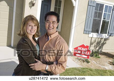 Stock Image - Couple in front of new house, portrait. Fotosearch