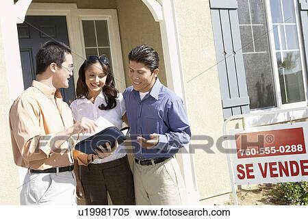 Couple looking at information in front of new home View Large Photo Image Stock Photography - Couple looking at information in front of new home. Fotosearch