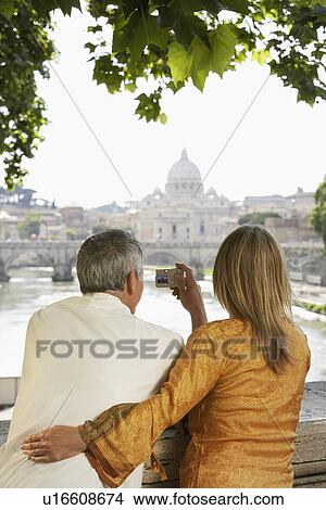 Couple on bridge photographing cathedral in Rome, Italy, back view View Large Photo Image Picture - Couple on bridge photographing cathedral in Rome, Italy, back view. Fotosearch
