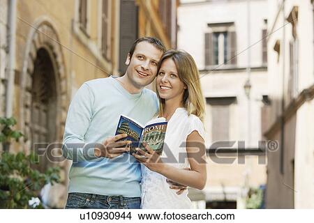Couple on street in Rome, Italy, holding guidebook, front view View Large Photo Image Picture - Couple on street in Rome, Italy, holding guidebook, front view. Fotosearch