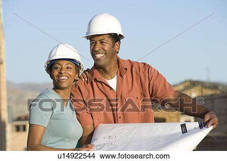 Couple over blueprint in construction site View Large Photo Image Picture - Couple over blueprint in construction site. Fotosearch