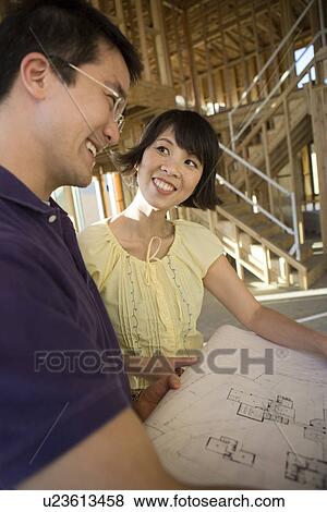 Couple over blueprint in construction site View Large Photo Image Stock Photo - Couple over blueprint in construction site. Fotosearch