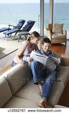 Stock Image - Couple reading newspaper at home, elevated view.. Fotosearch