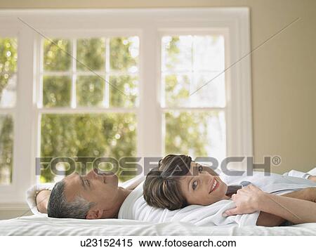 Couple relaxing in bed View Large Photo Image Stock Photography - Couple relaxing in bed. Fotosearch