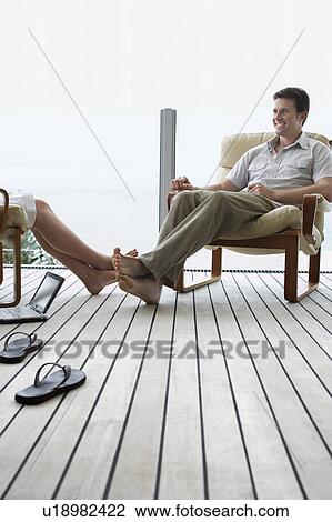 Stock Image - Couple relaxing on porch.. Fotosearch