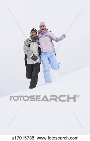 Couple running down snow-covered hill, low angle view View Large Photo Image Stock Photo - Couple running down snow-covered hill, low angle view. Fotosearch