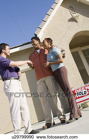 Couple shaking hands with estate agent outside their new home View Large Photo Image Stock Image - Couple shaking hands with estate agent outside their new home. Fotosearch