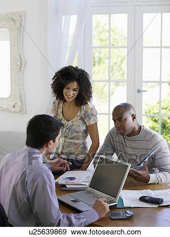 Couple sitting at dining table with financial advisor View Large Photo Image Stock Photo - Couple sitting at dining table with financial advisor. Fotosearch