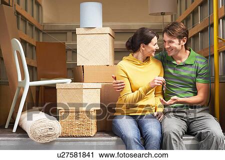 Stock Image - Couple Sitting in Back of Moving Van, handing over keys. Fotosearch