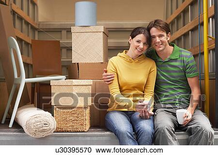 Stock Image - Couple Sitting in Back of Moving Van. Fotosearch
