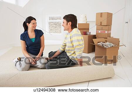 Couple sitting on half-rolled carpet in new home View Large Photo Image Stock Photo - Couple sitting on half-rolled carpet in new home. Fotosearch